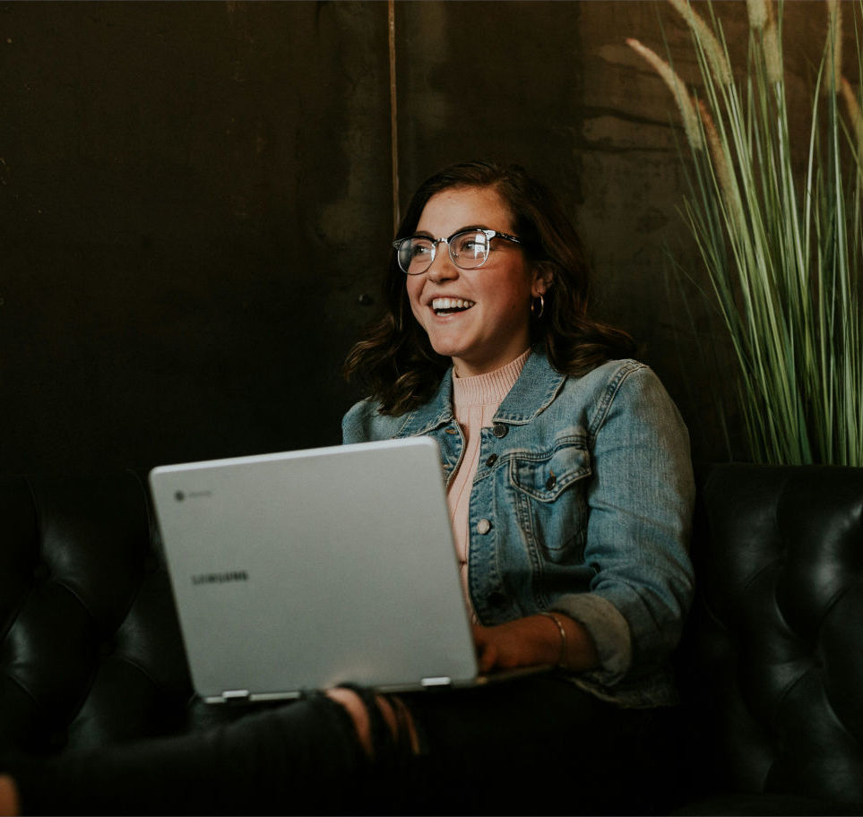 Una mujer joven usando una laptop y sonriendo